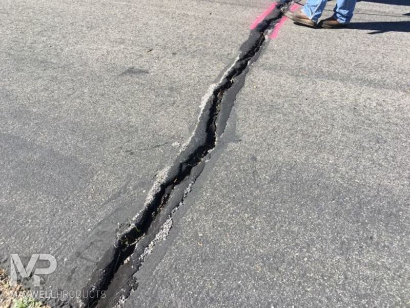 A wide crack in asphalt pavement.