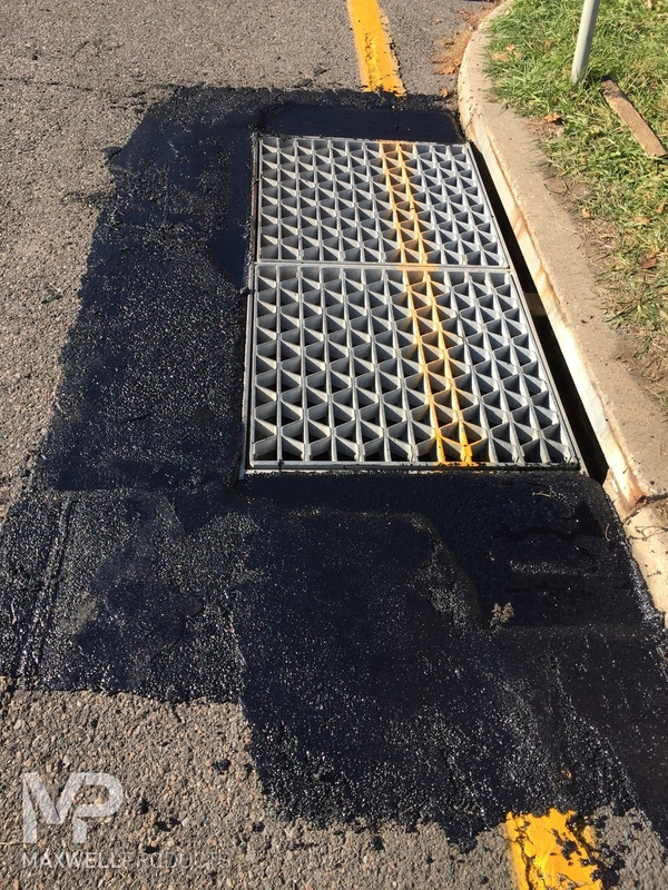 The pavement around a street drain is repaired with GAP Mastic.